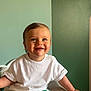toddler, child, smiling, sitting, white_tshirt, striped_shorts, green_wall, wooden_letters, name_sign, indoor, chair, happy, cute, portrait, person, baby, short_hair, skin, face, room