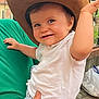Sacha participe au concours pour gagner de l'argent avec cette photo : baby, child, cowboy_hat, smiling, person, outdoor, green_shirt, hand, face, expression, fence, trees, sign, holding, cute, happy, white_shirt, striped_pants, foot, adult_hand