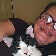 Angel Joy is registered to the contest to win money with this photo: animal, black_and_white_cat, cat, closeup, comfortable, content, cozy, eyewear, facial_expression, glasses, happy, human, indoor, person, pet, portrait, relaxed, smile, snuggle, tattoo