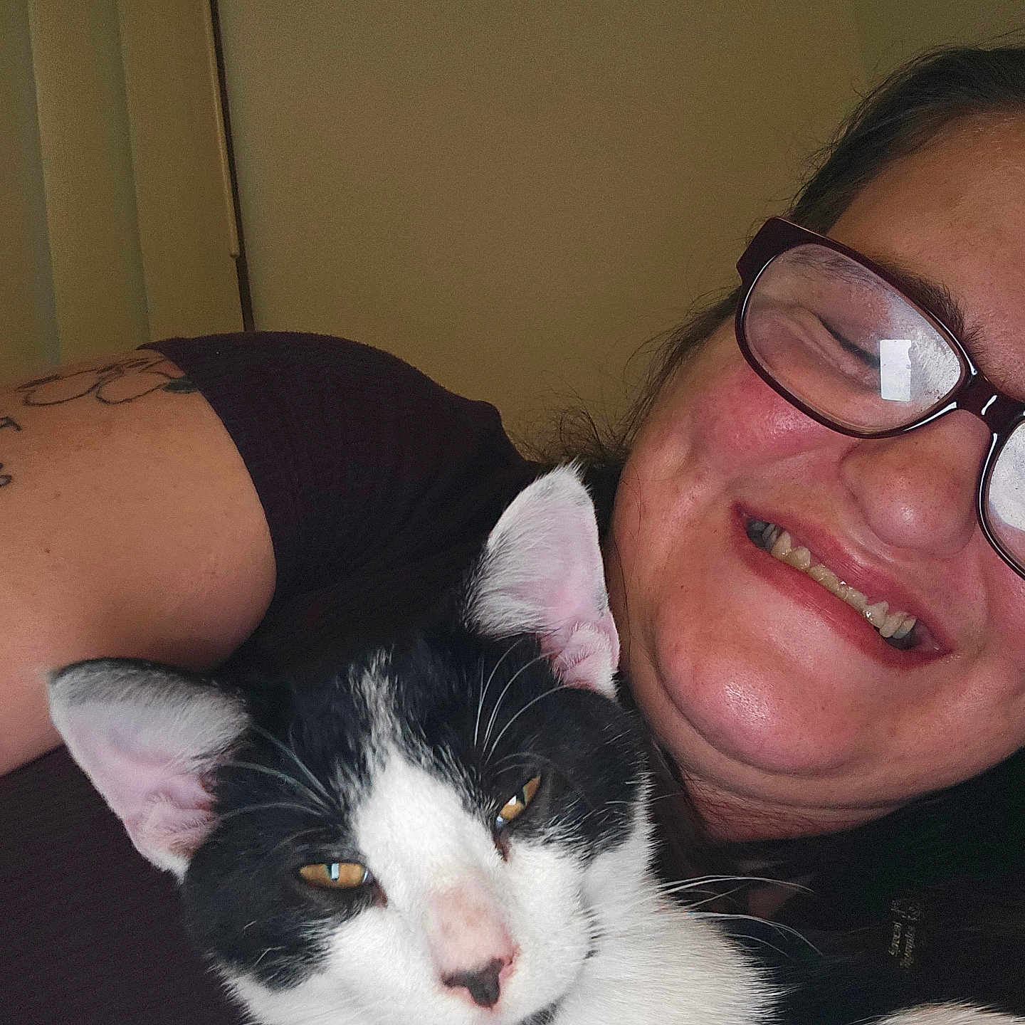 Angel Joy is registered to the contest to win money with this photo: animal, black_and_white_cat, cat, closeup, comfortable, content, cozy, eyewear, facial_expression, glasses, happy, human, indoor, person, pet, portrait, relaxed, smile, snuggle, tattoo