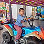 child, amusement_park, bumper_car, ride, colorful, lights, fun, playful, casual_clothing, sneakers, indoor, entertainment, young_boy, vehicle, toy, smile, activity, leisure, happy, person