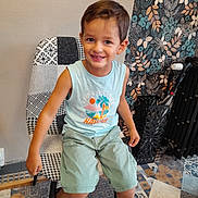 Naëlyo a rejoint le concours — aidez-le/la à gagner de superbes lots ! child, boy, smile, sitting, chair, patchwork, indoor, floor, patterned_floor, wallpaper, floral_wallpaper, shorts, sandals, clothing, happy, portrait, person, casual, home, furniture