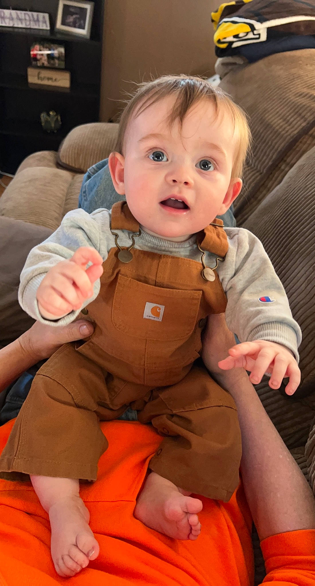 Karter is registered to the contest to win money with this photo: arm, baby, baby_toddler_clothing, cheek, child, comfort, eye, face, finger, flooring, hand, head, human_body, leg, mouth, orange, person, sitting, skin, sleeve