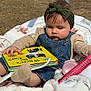 Allyanna is registered to the contest to win money with this photo: baby, child, headband, denim_overalls, book, outdoor, blanket, car, grass, seat, toy, person, infant, cute, reading, sunlight, nature, playtime, casual, focus