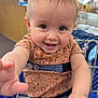 baby, child, shopping_cart, pigtails, smiling, cute, indoor, clothing, jeans, leopard_print, person, hand, face, happy, retail, store, seatbelt, metal, holding, portrait