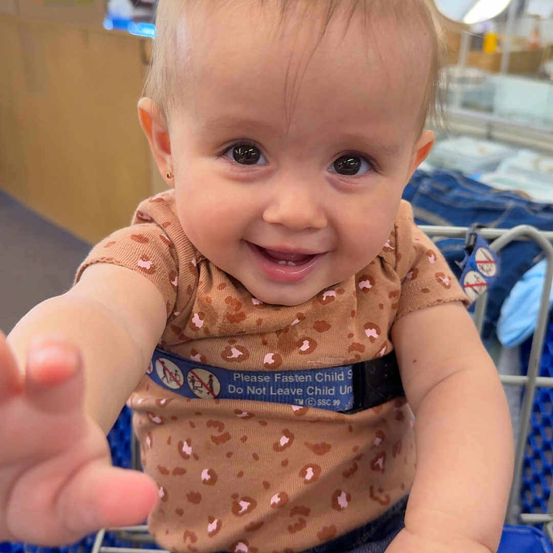 Allyanna joined the competition — help win amazing prizes! baby, child, clothing, cute, face, hand, happy, holding, indoor, jeans, leopard_print, metal, person, pigtails, portrait, retail, seatbelt, shopping_cart, smiling, store
