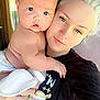 Mollie is registered to the contest to win money with this photo: baby, woman, portrait, face, holding, diaper, tattoo, outdoor, porch, natural_light, expression, skin, blonde_hair, casual_clothing, closeup, human, parent, child, candid, affection