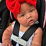 baby, infant, red_bow, headband, car_seat, white_clothing, blanket, curious_expression, child, seatbelt, closeup, face, skin, arm, hand, indoor, portrait, cute, chubby_cheeks, young