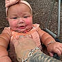 Mollie is registered to the contest to win money with this photo: arm, baby, bracelet, casual, child, cute, expression, face, grass, hand, headband, holding, infant, outdoor, person, pink_clothing, playground, summer, tattoo, woodchips