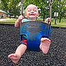 baby, child, swing, playground, joy, smile, barefoot, outdoor, park, trees, grass, daylight, fun, happy, person, metal_chains, clothing, shorts, blue, green