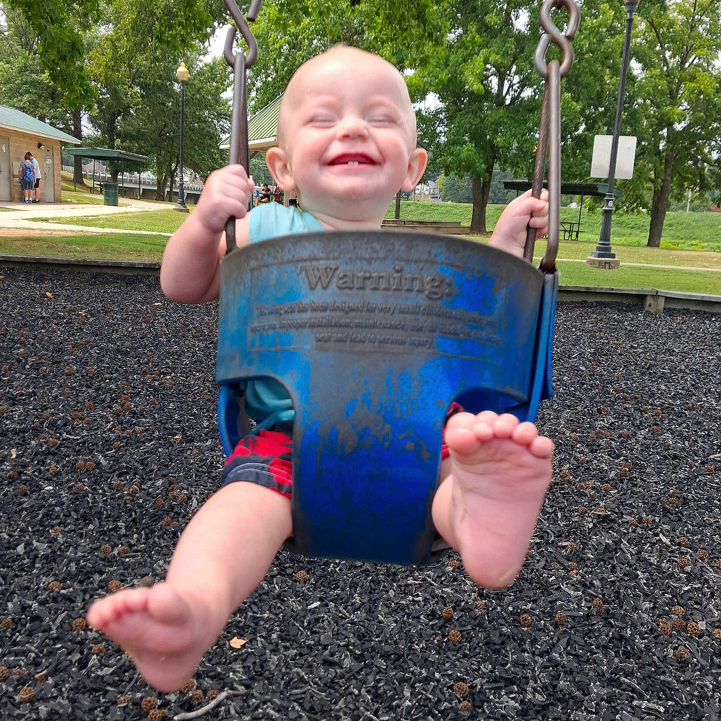 Wayln is registered to the contest to win money with this photo: baby, child, swing, playground, joy, smile, barefoot, outdoor, park, trees, grass, daylight, fun, happy, person, metal_chains, clothing, shorts, blue, green