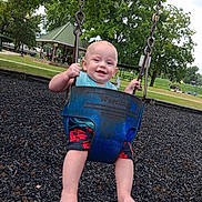 Wayln is registered to the contest to win money with this photo: baby, child, swing, playground, park, outdoor, smiling, happy, greenery, trees, summer, casual_clothing, barefoot, metal_chains, blue_swing, grass, pavilion, recreation, fun, daytime
