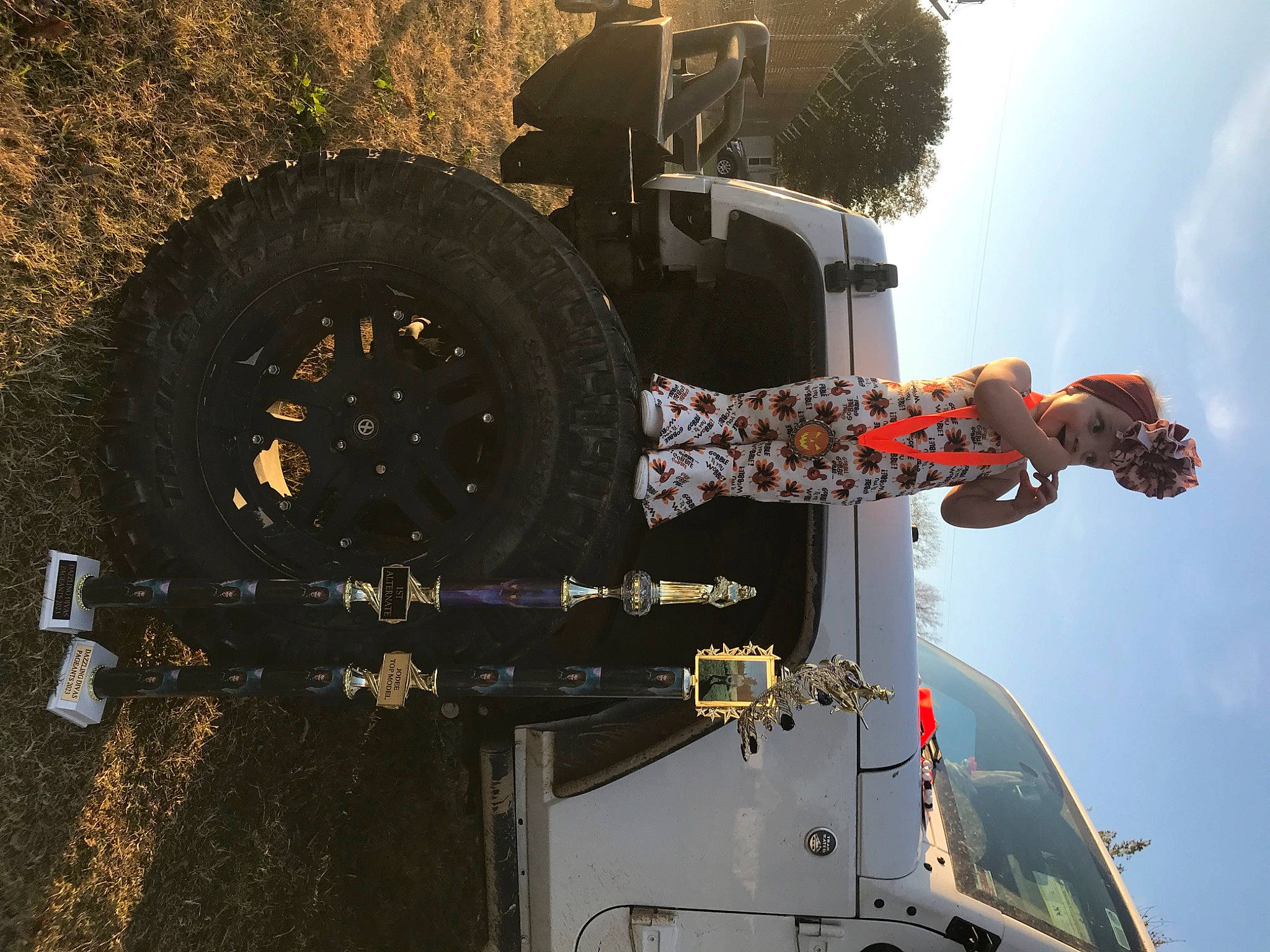 Jodee is registered to the contest to win money with this photo: asphalt, auto_part, automotive_exterior, automotive_tire, automotive_wheel_system, cloud, engineering, fender, headwear, machine, motor_vehicle, person, rim, rolling, sky, soil, stunt_performer, tire, tread, tree