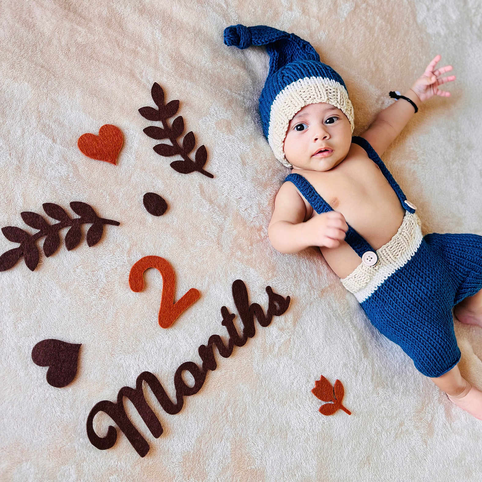 Rakan participe au concours pour gagner de l'argent avec cette photo : 2_months, age_milestone, baby, baby_boy, blanket, blue_hat, cute, felt_decorations, happy, hearts, indoor, infant, infant_fashion, knitted_clothing, leaves, lying_down, portrait, small_feet, small_hands, soft_texture