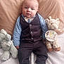 baby, infant, child, plush_toy, giraffe_toy, elephant_toy, clothing, vest, bow_tie, pants, shoes, blanket, pillow, sitting, portrait, indoors, soft_lighting, cute, 4_months, face
