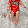 baby, infant, red_onesie, dinosaur_print, smiling, lying_down, fluffy_blanket, white_background, wooden_marker, age_marker, cute, happy, child, portrait, indoors, soft_texture, small_person, human, one_person, casual_clothing