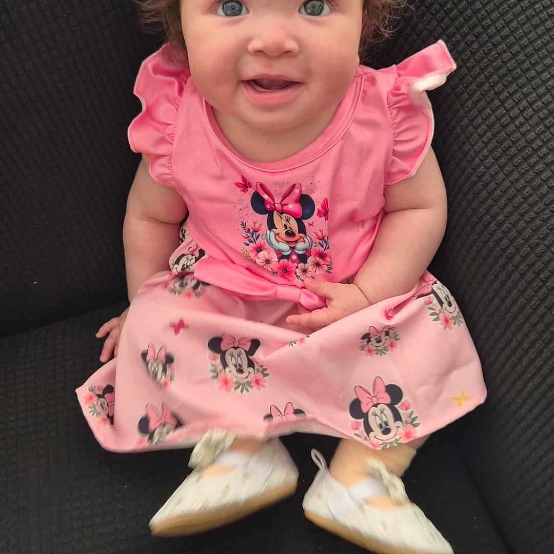 Vanity is registered to the contest to win money with this photo: baby, child, curly_hair, dress, pink, minnie_mouse, shoes, smile, sitting, chair, indoor, cute, happy, person, portrait, infant, young_child, clothing, fashion, eyes
