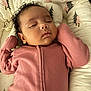 baby, sleeping, pink_clothing, curly_hair, infant, cozy, cushion, baby_lounger, pattern, tree_design, soft_texture, peaceful, newborn, child, portrait, indoors, cute, resting, toddler, comfort