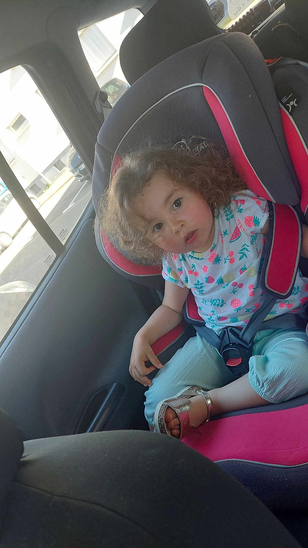 élyanor a rejoint le concours — aidez-le/la à gagner de superbes lots ! blue_pants, car_interior, car_seat, casual_clothing, child, curly_hair, daylight, gray, parking_lot, person, pink, road, safety, sandal, seat, seatbelt, toddler, vehicle, window, young_child