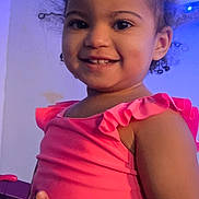 Lilyana is registered to the contest to win money with this photo: toddler, child, smiling, curly_hair, pink_top, indoor, technology, screen, notification_bar, happy, portrait, person, young_child, cute, holding_object, blue_light, casual_clothing, playful, fun, home