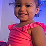 toddler, child, smiling, curly_hair, pink_top, indoor, technology, screen, notification_bar, happy, portrait, person, young_child, cute, holding_object, blue_light, casual_clothing, playful, fun, home