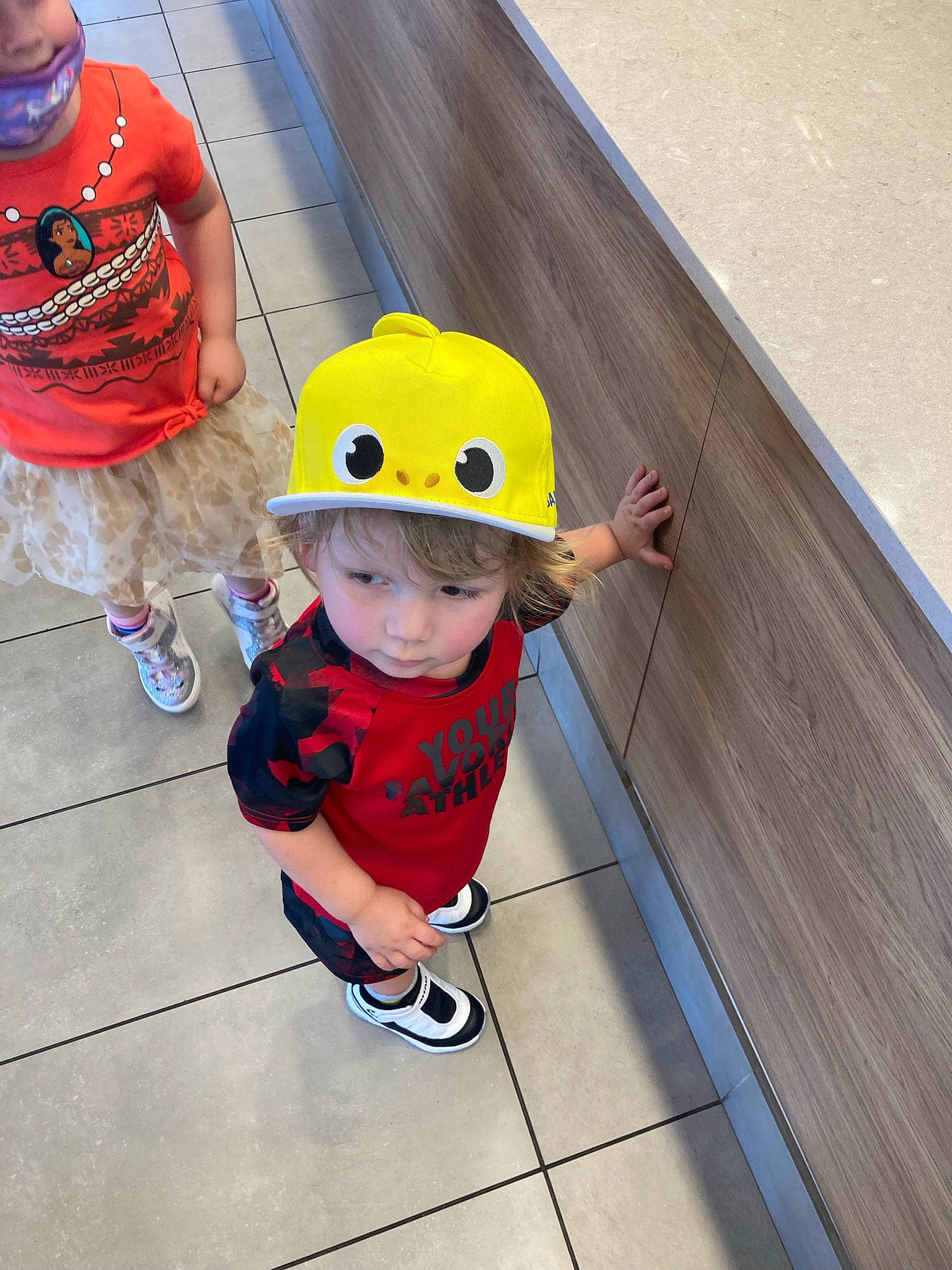 Kenneth is registered to the contest to win money with this photo: baby_toddler_clothing, child, composite_material, electric_blue, floor, flooring, fun, happy, headwear, leg, leisure, person, personal_protective_equipment, play, recreation, sandal, shoe, shorts, sneakers, t_shirt