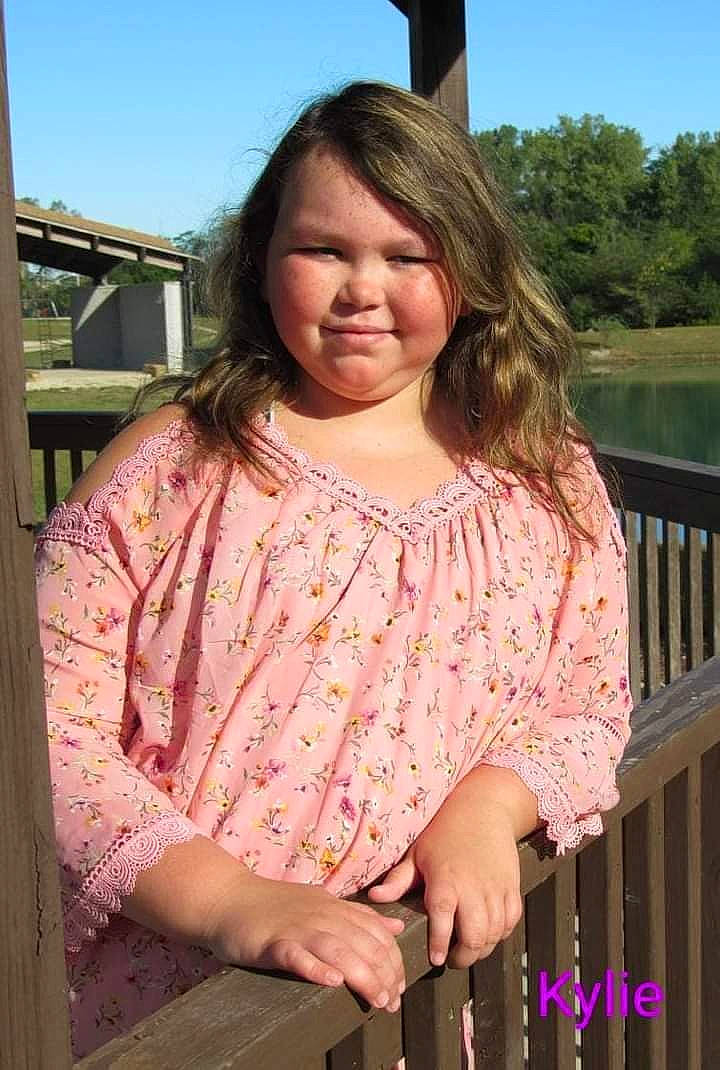 Kylie is registered to the contest to win money with this photo: art, blond, blouse, brown_hair, child_model, clothing, crochet, finger, joy, knitting, long_hair, neck, outerwear, pattern, person, pink, shoulder, sleeve, smile, textile