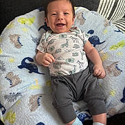 Axel joined the competition — help win amazing prizes! baby, infant, smiling, onesie, pants, socks, blanket, dinosaur_pattern, cute, happy, child, lying_down, soft_texture, indoor, cozy, person, face, head, small_hands, feet