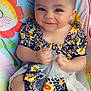 baby, bodypart, clothing, cushion, cutlery, dress, face, finger, furniture, hand, happy, head, homedecor, person, photography, portrait, shorts, sitting, smile, spoon