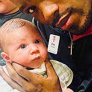 Donnie joined the competition — help win amazing prizes! baby, man, holding, portrait, face, hand, tattoo, person, infant, closeup, looking, indoor, expression, love, bonding, skin, clothing, jacket, name_badge, gentle