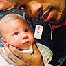 baby, man, holding, portrait, face, hand, tattoo, person, infant, closeup, looking, indoor, expression, love, bonding, skin, clothing, jacket, name_badge, gentle