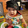baby, child, infant, cap, hat, baby_walker, toy, colorful, indoor, kitchen, floor, cabinet, wooden_floor, curious, looking, sitting, person, clothing, play, young