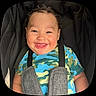 Xylo-King is registered to the contest to win money with this photo: baby, child, smiling, curly_hair, car_seat, camouflage_shirt, happy, face, infant, safety_harness, cute, portrait, young_child, seat_strap, indoor, close_up, person, apparel, cheerful, toddler