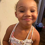 Suelena joined the competition — help win amazing prizes! child, girl, smile, curly_hair, dress, indoor, face, portrait, earrings, happy, person, young, accessory, necklace, skin, standing, background, door, floor, room