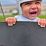 baby, helmet, swing, outdoor, child, smile, happy, playground, hands, face, joy, person, clothing, red, blue, background, blur, fun, cute, infant