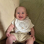 Elijah is registered to the contest to win money with this photo: baby, smiling, infant, bib, clothing, couch, blanket, happy, sitting, indoor, child, person, cute, skin, face, head, hand, foot, expression, comfort