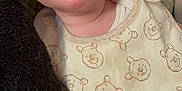 Elijah is registered to the contest to win money with this photo: baby, infant, face, eyes, bib, clothing, bear_pattern, blanket, cushion, soft_texture, closeup, portrait, cute, rosy_cheeks, indoors, child, person, smiling, white_clothing, cozy