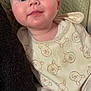 baby, infant, face, eyes, bib, clothing, bear_pattern, blanket, cushion, soft_texture, closeup, portrait, cute, rosy_cheeks, indoors, child, person, smiling, white_clothing, cozy