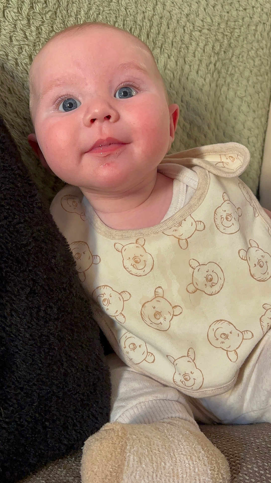 Elijah is registered to the contest to win money with this photo: baby, infant, face, eyes, bib, clothing, bear_pattern, blanket, cushion, soft_texture, closeup, portrait, cute, rosy_cheeks, indoors, child, person, smiling, white_clothing, cozy