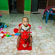 Mohammad Ridwan is registered to the contest to win money with this photo: toddler, child, toy, rocking_horse, indoor, floor_tiles, green_wall, wooden_door, plastic_chair, scattered_toys, curious, baby, playtime, furniture, footwear, cabinet, colorful, flooring, person, head