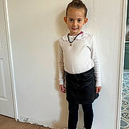 Lya participe au concours pour gagner de l'argent avec cette photo : child, girl, standing, white_sweater, black_skirt, black_leggings, white_boots, smiling, indoor, wooden_floor, plain_wall, necklace, fashion, portrait, young, cute, hair_up, earrings, casual, confident