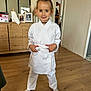 child, girl, karate, martial_arts, white_gi, belt, smiling, indoors, wooden_floor, dresser, mirror, photograph, portrait, standing, socks, home, furniture, room, happy, casual