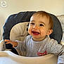 baby, high_chair, smiling, indoor, child, person, clothing, face, happy, young_child, home, furniture, seat, cute, expression, infant, portrait, table, hand, light