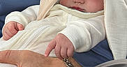 Anastasia is registered to the contest to win money with this photo: baby, sleeping, infant, white_clothing, bunny_ears, hand, adult, bracelet, blue_jacket, cozy, closeup, peaceful, cuddling, portrait, soft_light, fingers, skin, person, rest, comfort