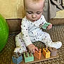 Bryson is registered to the contest to win money with this photo: baby, blanket, carpet, child, colorful, couch, cute, floor, focused, hand, home, indoor, infant, pajamas, pattern, playtime, sitting, stacking_toy, toy, wooden_toy