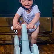 Bryson is registered to the contest to win money with this photo: baby, balance_bike, blue, child, face, floor, footwear, happy, helmet, helmet_strap, indoor, person, play, riding, short_sleeve, smile, toddler, toy, wooden_floor, young_child