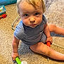 child, toddler, indoor, carpet, toy, person, blue_eyes, blonde_hair, striped_clothing, sitting, floor, playtime, cute, looking_up, baby_toys, carpet_texture, casual_wear, young_child, home, curious_expression