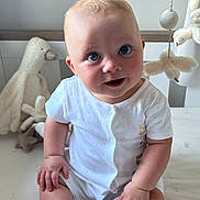 Arlo is registered to the contest to win money with this photo: baby, blue_eyes, child, curious, cute, face, hand, indoor, infant, light, milestone_card, nursery, plush_toy, sitting, skin, smiling, soft_toys, white_clothing, wooden_furniture, young