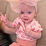 baby, blue_eyes, bow, child, couch, cute, face, hand, headband, indoor, infant, patterned_shirt, person, pink_clothing, pink_pants, playful, sitting, smiling, soft_lighting, young_child