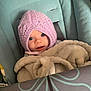 Dorothea is registered to the contest to win money with this photo: baby, infant, knit_hat, blanket, car_seat, blue_eyes, child, cozy, cute, young_child, soft_texture, warm_clothing, indoor, portrait, smiling, person, seat_belt, fabric, headwear, wrapped